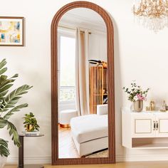 a living room with a large mirror on the wall next to a couch and potted plant