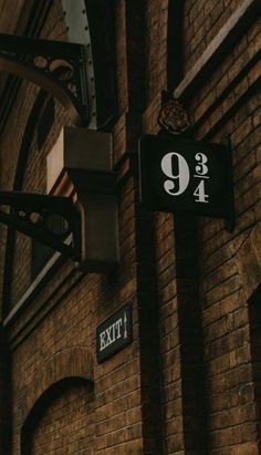 an exit sign on the side of a brick building next to a street light and clock