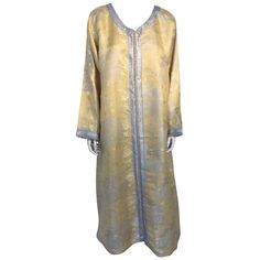 Evening or interior metallic gold brocade dress kaftan with silver and gold trim. Hand-made ceremonial caftan from North Africa, Morocco. Vintage exotic 1970s silver metallic brocade caftan gown. The luminous gold metallic caftan maxi dress caftan is made in a subtle metallic floral patterned brocade with shades of gold and silver, with running down the centre round braided gold buttons from the neckline to the hemline. Princess seams, fully front gold thread buttoning with 99 gold hand-knotted Gold Silk Kaftan For Festive Season, Festive Gold Silk Kaftan, Elegant Yellow Kaftan For Festive Occasions, Festive Gold Kaftan For Festive Occasions, Gold Festive Kaftan, Festive Gold Kaftan For Festive Seasons, Gold Floor-length Kaftan For Festive Occasions, Gold Embroidered Kaftan With Traditional Drape, Traditional Gold Floor-length Thobe