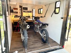 two motorcycles parked in the back of a trailer