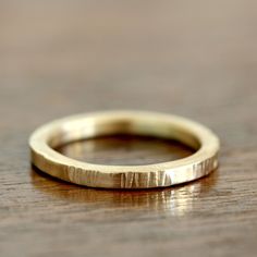 a gold wedding ring sitting on top of a wooden table