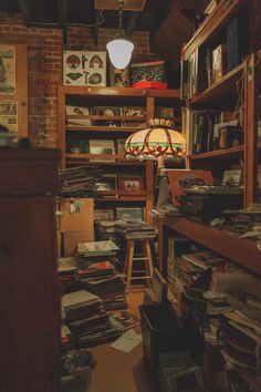 a room filled with lots of clutter next to a lamp and bookshelf