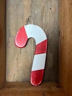 a red and white wooden letter shaped like a candy cane on a shelf in a wood frame