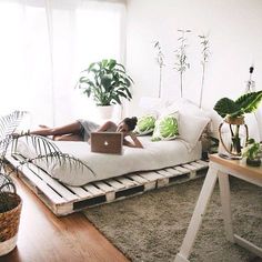 a person laying on a couch with a laptop in front of them and some plants