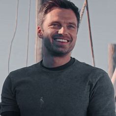 a man smiling while standing on top of a boat