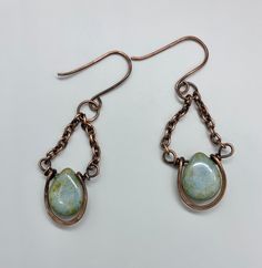 Beautiful blue with a touch of green Czech Glass drops, surrounded by hammered copper. These are dangling from copper chain and hang on handmade ear wires.Approximately 1 5/8" long and 7/8" wideThese earrings have been antiqued, polished and sealed.Sealed with Protectaclear ProtectaClear is a clear, protective coating that is tough enough to protect jewelry and is safe for wear against skin. ProtectaClear is practically invisible once applied and will seal and protect jewelry from tarnish, oxida Copper Dangle Earrings With Patina, Copper Dangle Jewelry With Patina, Copper Teardrop Earrings With Patina, Bronze Teardrop Jewelry In Copper Wire, Metal Teardrop Jewelry With Patina, Teardrop Metal Jewelry With Patina, Hammered Copper, Copper Chain, Ear Wires