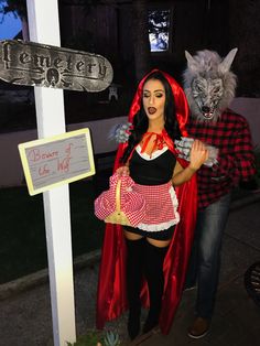 a woman in a costume standing next to a man with a wolf mask and red cape