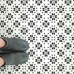 a person standing in front of a wall with black and white designs on the floor