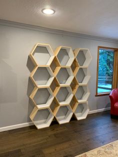 a room with a red chair and shelving unit on the wall next to a window