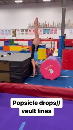 a person on a trampoline doing a handstand in an indoor gym