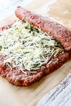 two pieces of pizza sitting on top of a piece of wax paper with grated cheese