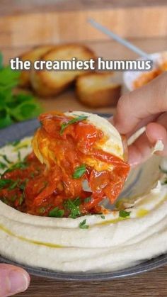 a person is dipping sauce on top of hummus