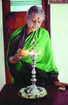 an old woman is lighting a candle on a small cake in the shape of a lamp