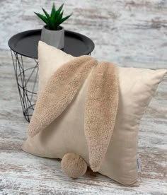 a pillow with a bunny ears on it next to a small potted cactus plant