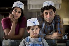 a man, woman and child wearing chef's hats in front of a counter