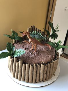 a dinosaur cake with chocolate frosting and greenery