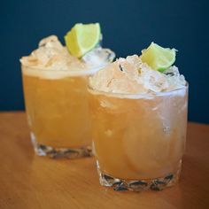 two glasses filled with drinks sitting on top of a wooden table