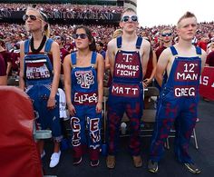 some people are standing in front of a crowd at a football game wearing matching outfits