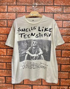 Vintage 90s Kurt Cobain "Smells Like Teen Spirit" Grunge Rock Legendary Memorial Photo T Shirt  / Vintage Band T Shirt  Condition : Good Used  Size on tag : M fit L Colour : White Brand : Unbrand Measurement : Armpit to armpit - 21.5" Length - 26" Material : Cotton Made In: Europe THE SHIPPING (Your Choice Please read) 1. The shipping cost is USD 20 via Malaysian Registered Postage With Tracking Number. It will take 2-4 weeks or more for delivery, depends on your custom checking. 2. Add USD 10 for speedy delivery via DHL Express Service.It will take 2-5 Working days to deliver. More safe!!  PLEASE LEAVE ME YOU PHONE NO. for DHL requirement (VERY IMPORTANT).  **Add USD 5 shipping for each additional items! THE PAYMENT We accept PayPal only. The item will be sent within 1-3 days after paymen Band Shirt Outfits Grunge, Band Tee Aesthetic, 90s Kurt Cobain, Band Shirt Outfits, Photo T Shirt, Vintage Rock Tees, Vintage Band T Shirts, Smells Like Teen Spirit, Rock T Shirt