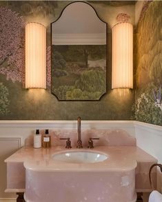 a bathroom sink sitting under a mirror next to a wall mounted light over it's vanity