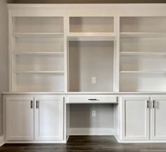 an empty room with white cabinets and wood floors