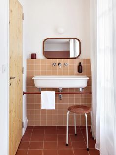 a white sink sitting under a bathroom mirror next to a wooden cabinet and counter top