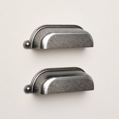 two metal handles on a white wall, one is black and the other is silver