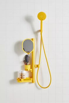 a yellow shower head, mirror and soap dispenser