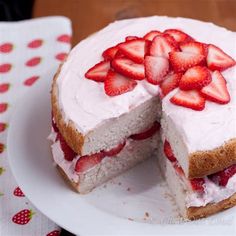 a cake with strawberries on top is cut in half and sits on a plate