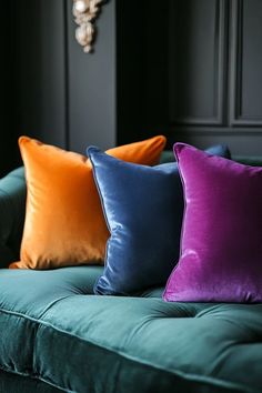 four different colored pillows sitting on top of a green couch