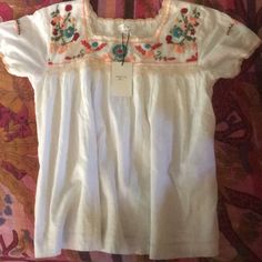 White With Colorful Flowers And Sleeve Trim. Fully Lined 100% Cotton Blouse. Casual Tops With Embroidered Border For Spring, White Embroidered Floral Top For Summer, White Embroidered Top With Floral Print For Summer, White Embroidered Neckline Top For Summer, Bohemian Spring Tops With Embroidered Border, Bohemian Tops With Embroidered Border For Spring, Summer Festival Peasant Top With Embroidered Hem, White Casual Peasant Top With Floral Embroidery, Casual White Peasant Top With Floral Embroidery