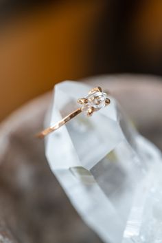 a diamond ring sitting on top of a white piece of glass in front of a wooden bowl