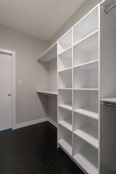 an empty walk in closet with white shelving