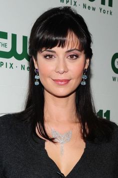 a woman with dark hair wearing blue earrings