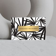 a black and white business card with gold foil on it next to two vases