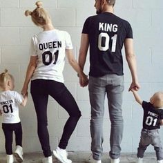 a man and two women holding hands while standing next to a little boy in front of a white brick wall