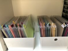 two bins filled with files on top of a white shelf next to each other