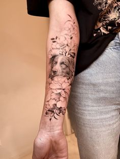 a woman's arm with flowers on it and a dog in the middle of her arm