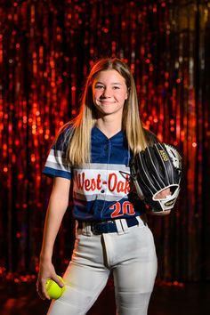 a young woman is posing for a photo with a softball glove and ball in her hand