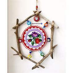 an ornament made out of branches with beads and flowers on it is hanging from the wall