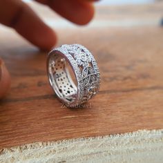 a close up of a ring on a wooden surface with a finger pointing at it