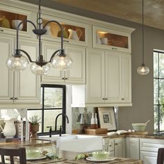 a kitchen filled with lots of counter top space and lights hanging from the ceiling above it