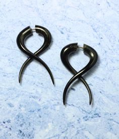 two pairs of black metal earrings on a marble surface