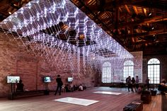 people are standing in the middle of a large room with wooden floors and lights hanging from the ceiling