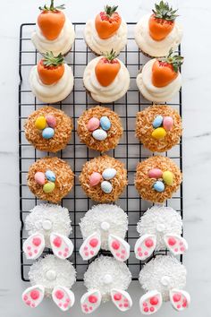 cupcakes decorated like bunny ears and carrots on a cooling rack with white frosting