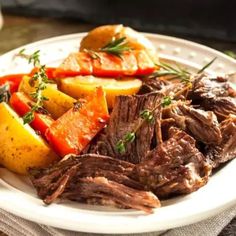 a white plate topped with roast, potatoes and carrots