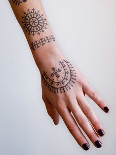 a woman's hand with a black and white tattoo design on her left arm