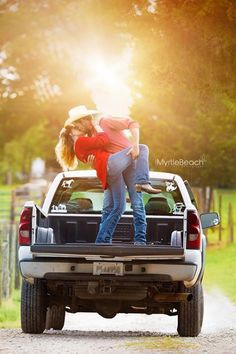 two people in the back of a pick up truck with their arms around each other