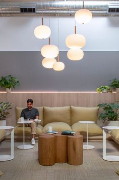 a man sitting on top of a couch in a living room next to two tables