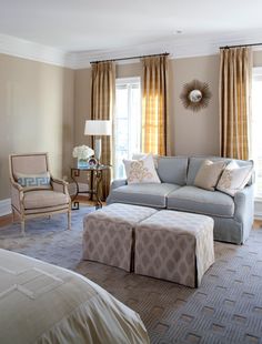 a living room filled with furniture next to a window covered in drapes and curtains